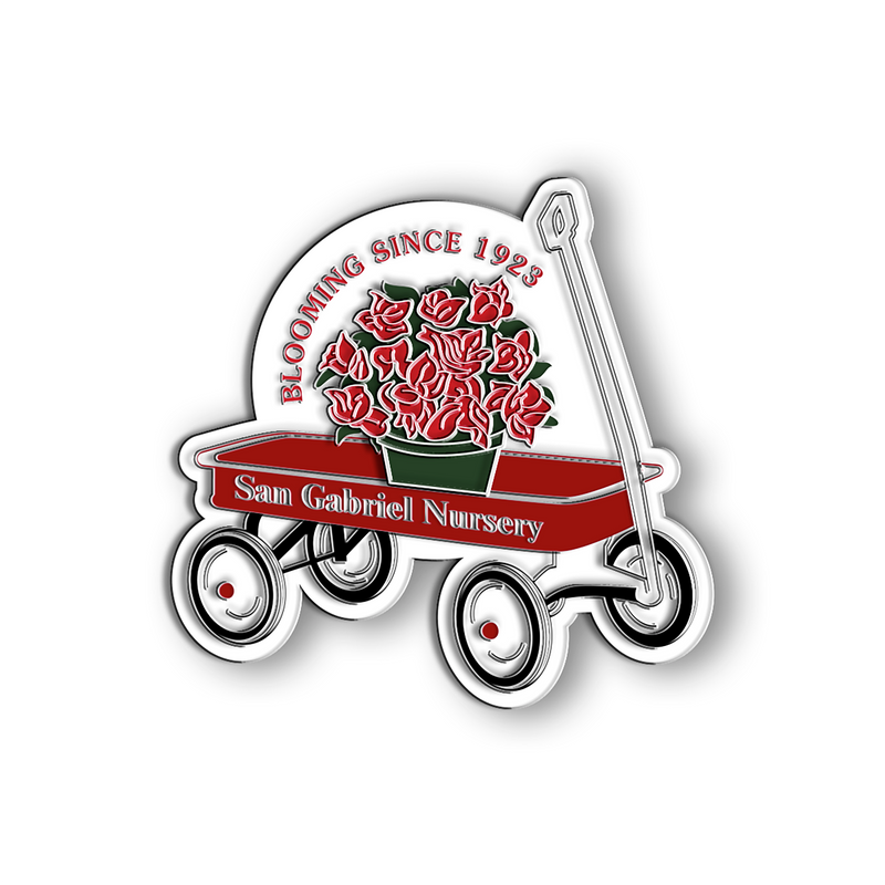 This is a hard enamel pin for the Anniversary pack, engraved showing a red wagon, red text that says Blooming since 1923 San Gabriel Nursery. Inside the red wagon graphic, there is a bucket of red azaleas.
