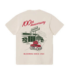 Tshirt that is written "100th anniversary, blooming since 1923". Featuring an illustration of San Gabriel Nursery & Florist storefront and signage. There is a red wagon that holds Mission Bell Azaleas.